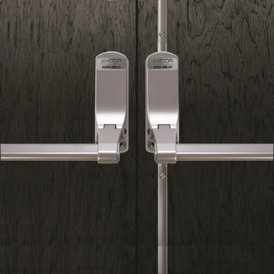 ASSA ABLOY Exidor panic bars fitted to dark timber double doors for emergency exit hardware.