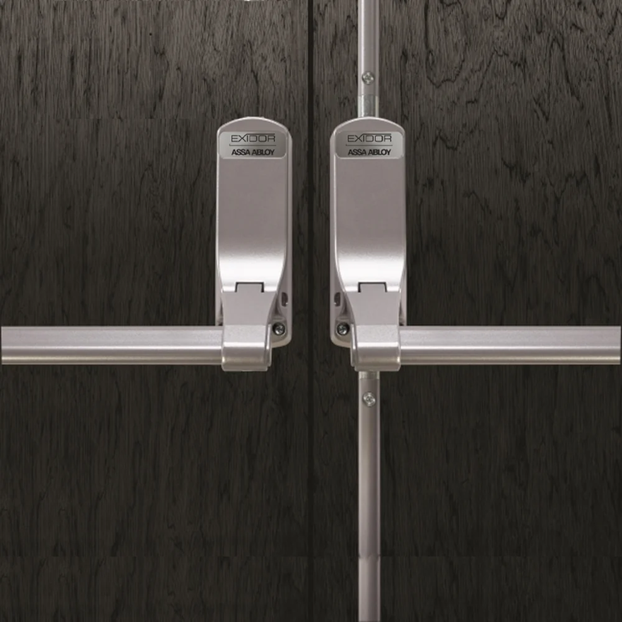 ASSA ABLOY Exidor panic bars fitted to dark timber double doors for emergency exit hardware.